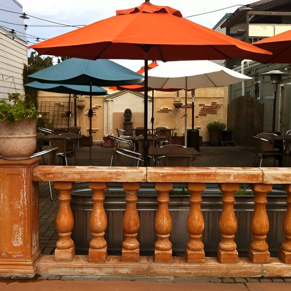 Batika India Bistro's outdoor patio with orange, blue, and white umbrellas over dining tables.