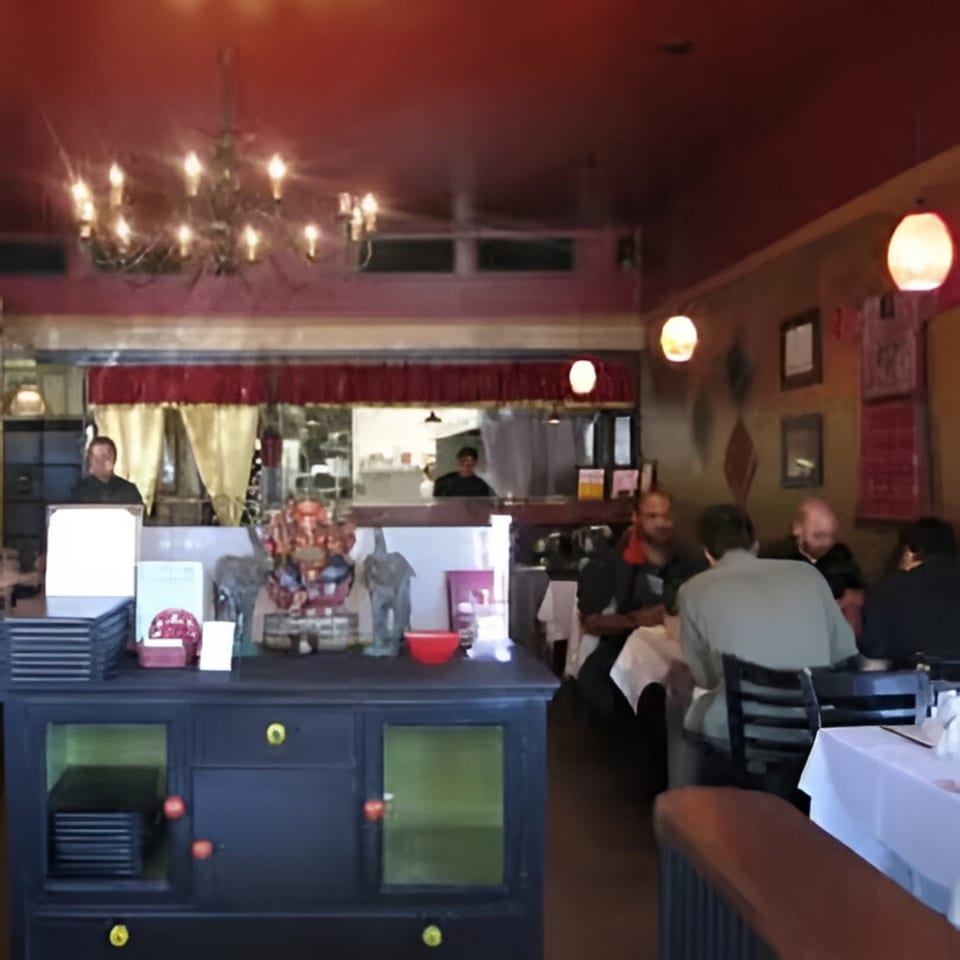The interior of Batika India Bistro, with patrons dining and a server behind the counter.