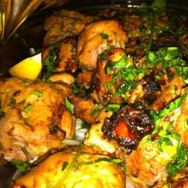 Close-up of Batika India Bistro's Indian chicken dish, garnished with fresh herbs and a lemon wedge.