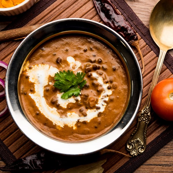 A bowl of Batika India Bistro's creamy Dal Makhani, garnished with fresh cilantro and a swirl of cream.