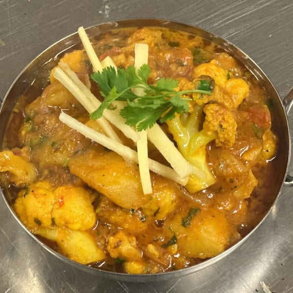 Batika India Bistro's Aloo Gobi, a vibrant Indian curry with potatoes and cauliflower, garnished with ginger and cilantro.