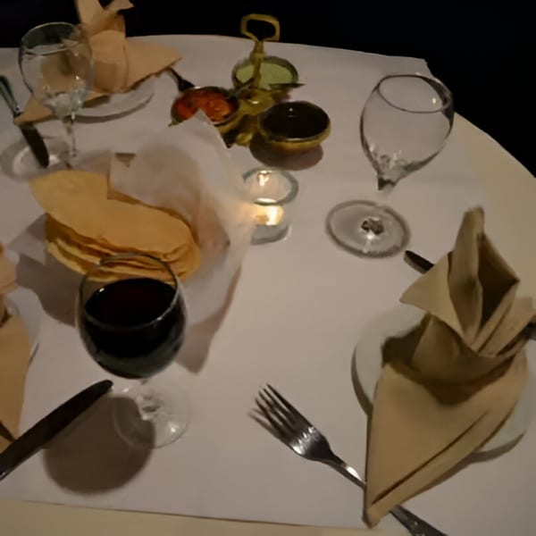 A table set for two at Batika India Bistro with wine, water, bread, and condiments.